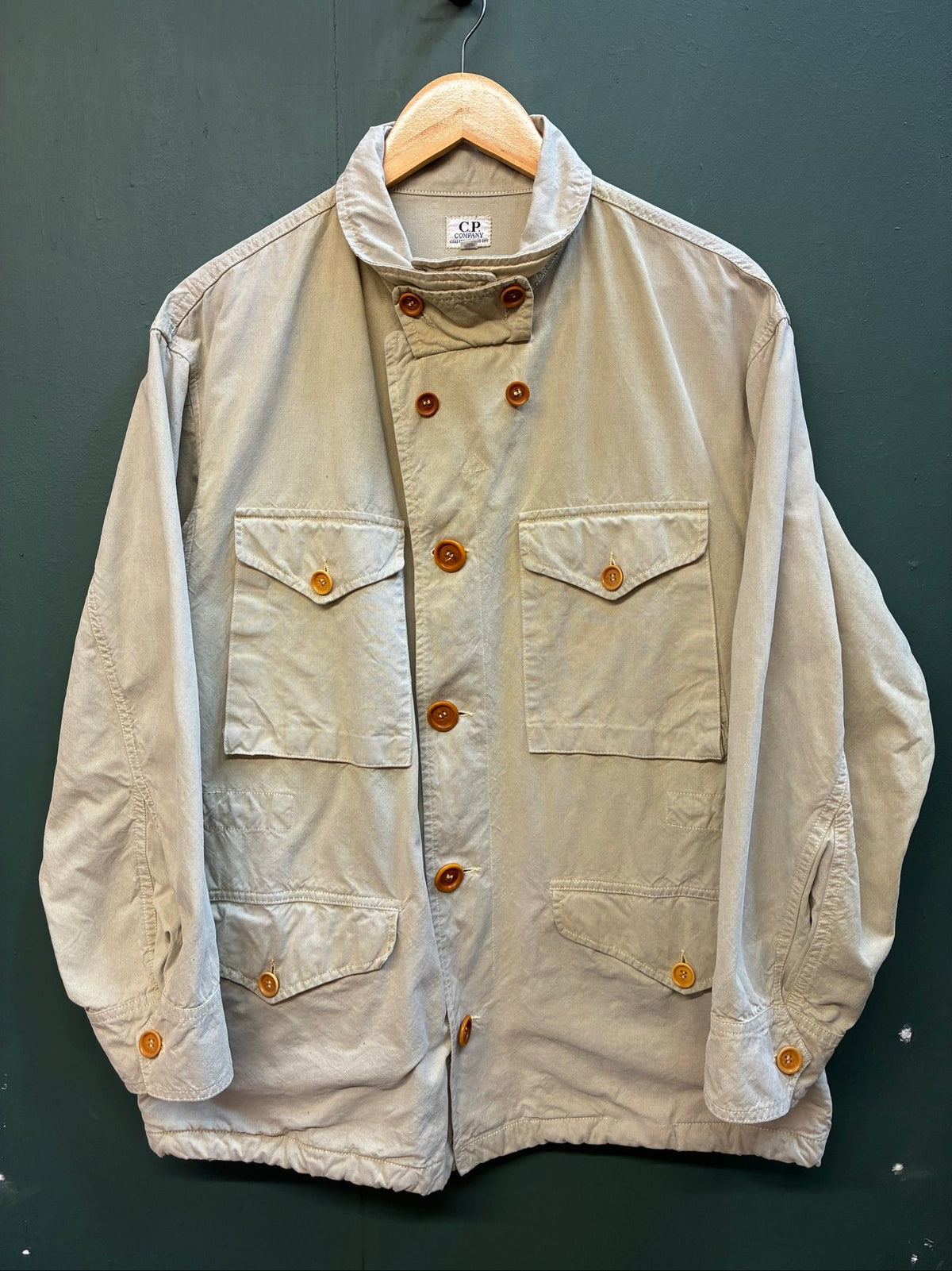 C.P. Company beige cotton field jacket with mild distress and green paint marks.