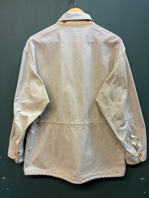 C.P. Company beige cotton field jacket with mild distress and green paint marks.