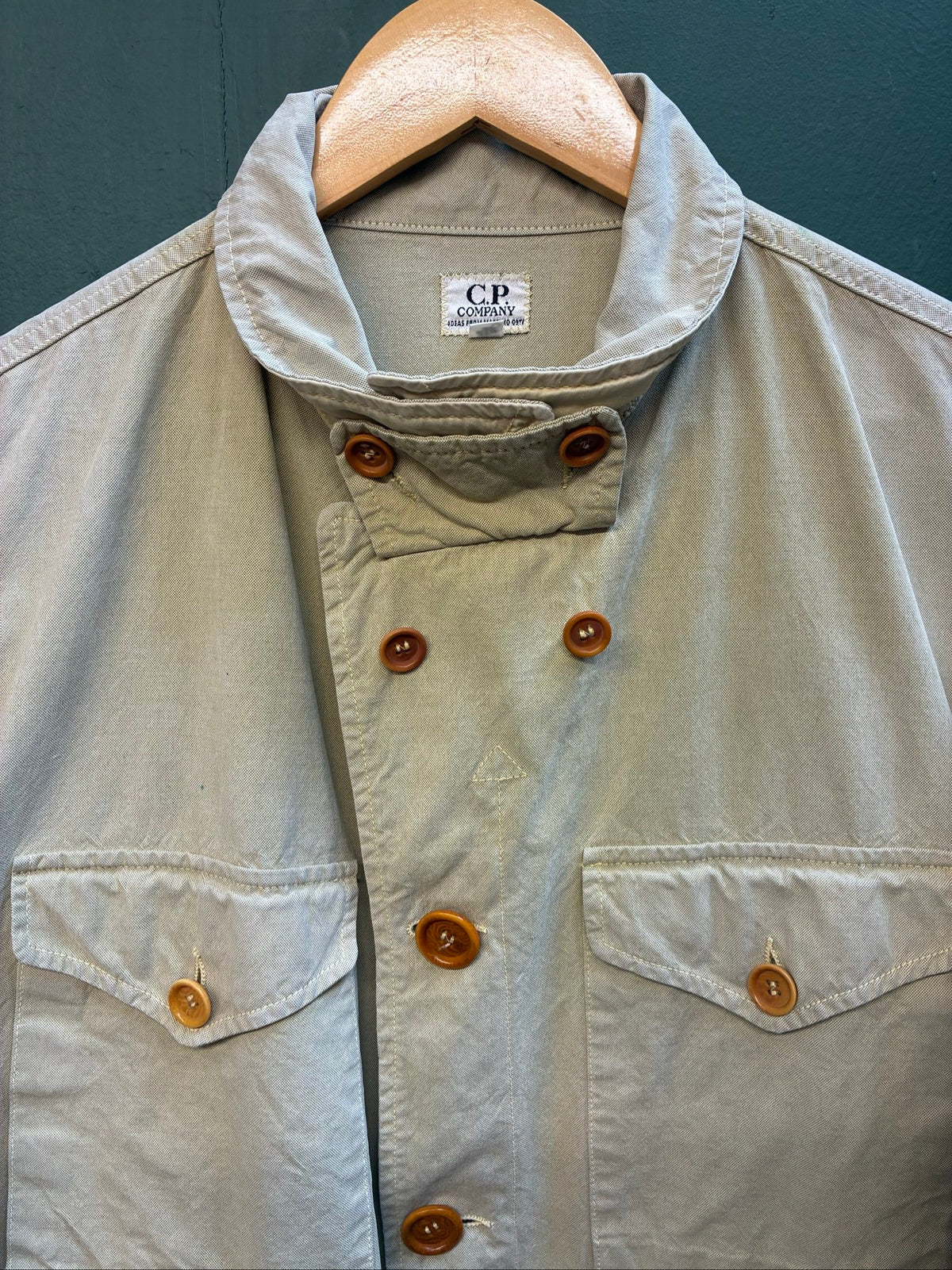 C.P. Company beige cotton field jacket with mild distress and green paint marks.