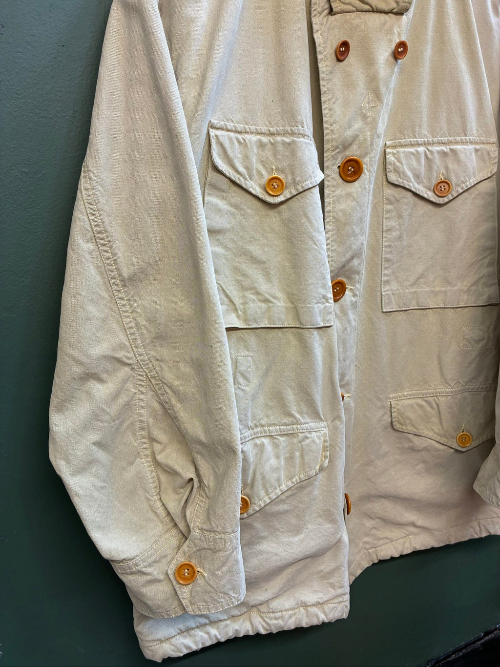 C.P. Company beige cotton field jacket with mild distress and green paint marks.