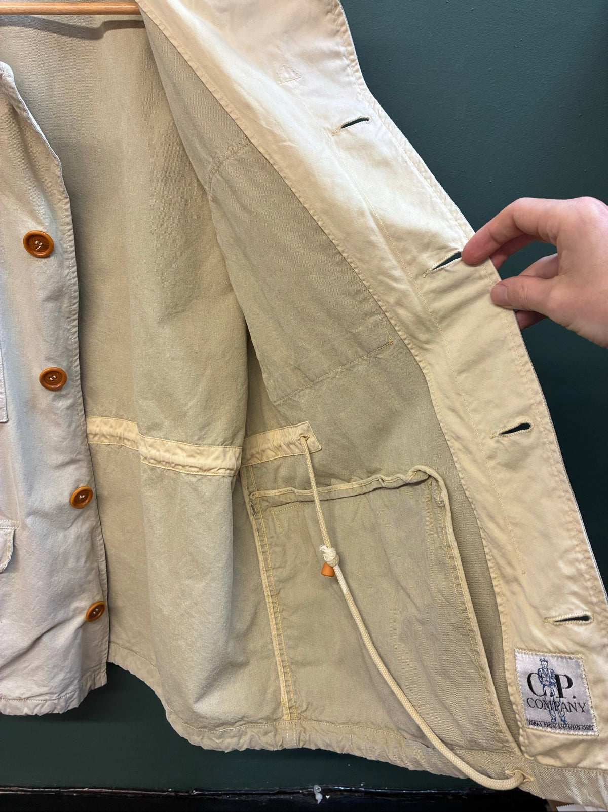 C.P. Company beige cotton field jacket with mild distress and green paint marks.