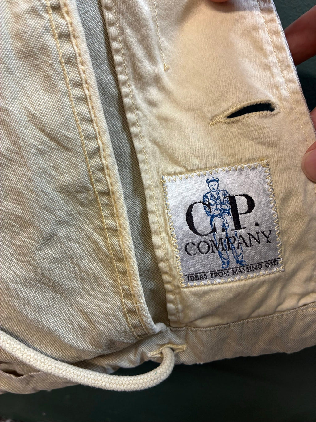 C.P. Company beige cotton field jacket with mild distress and green paint marks.