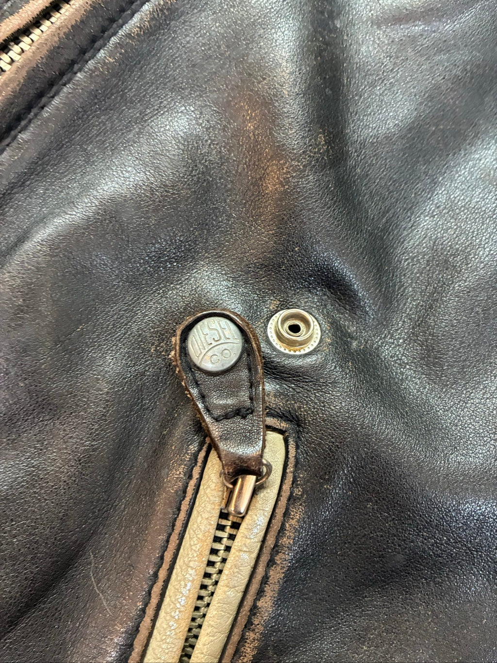 Diesel beige and black leather motorcycle jacket with quilted insulation and zipper pockets.