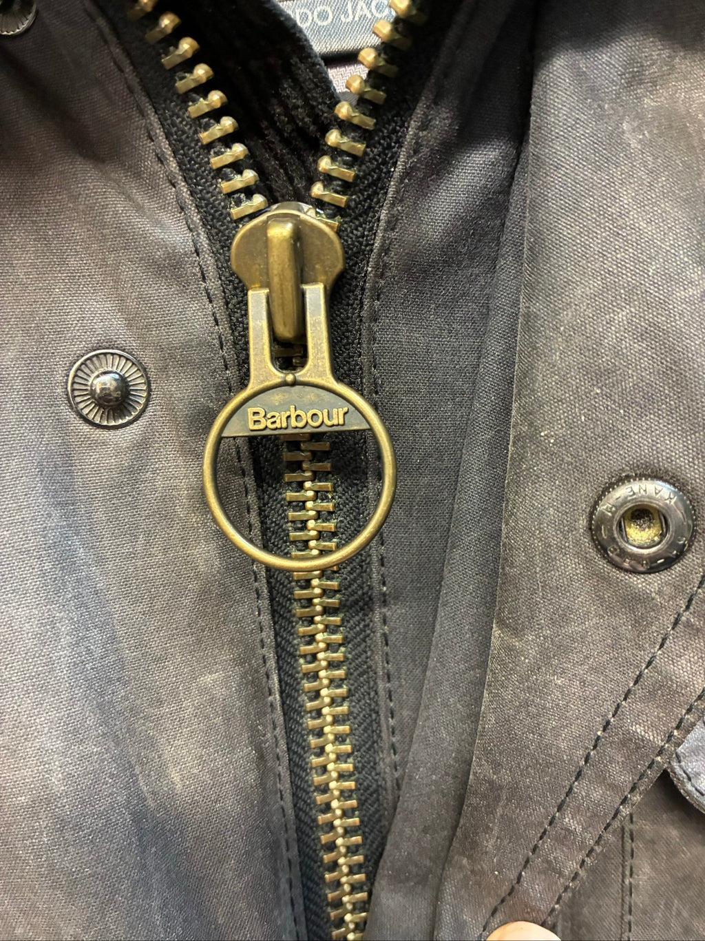 Barbour black and grey wax jacket with military utility design and made in England tag.