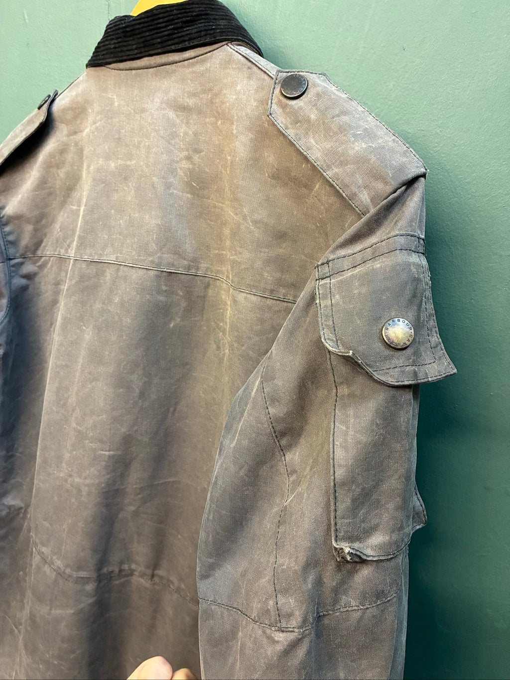 Barbour black and grey wax jacket with military utility design and made in England tag.