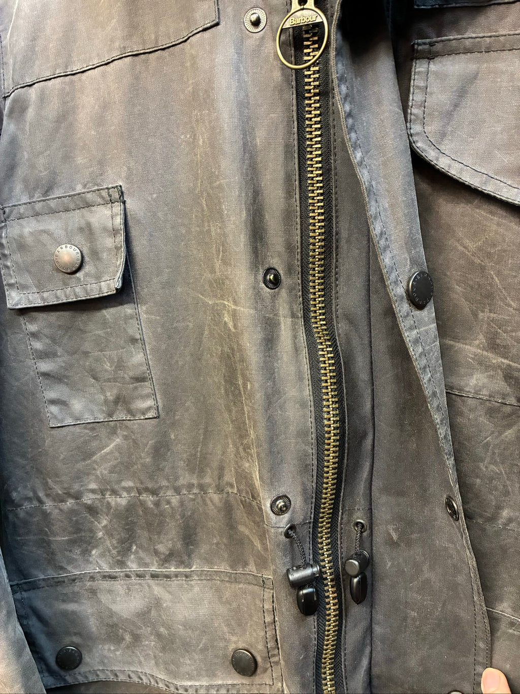 Barbour black and grey wax jacket with military utility design and made in England tag.