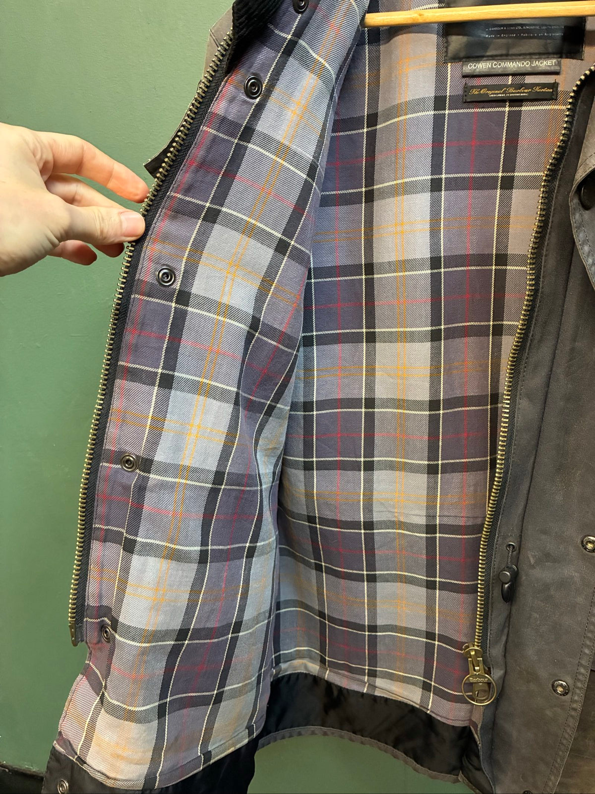 Barbour black and grey wax jacket with military utility design and made in England tag.