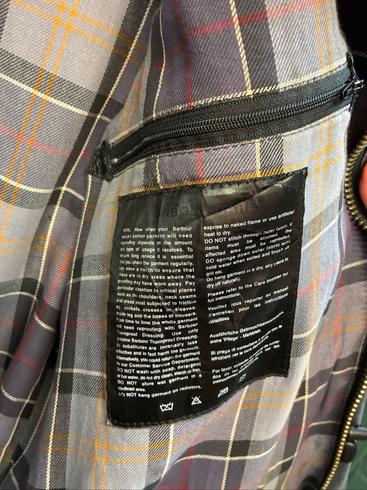 Barbour black and grey wax jacket with military utility design and made in England tag.