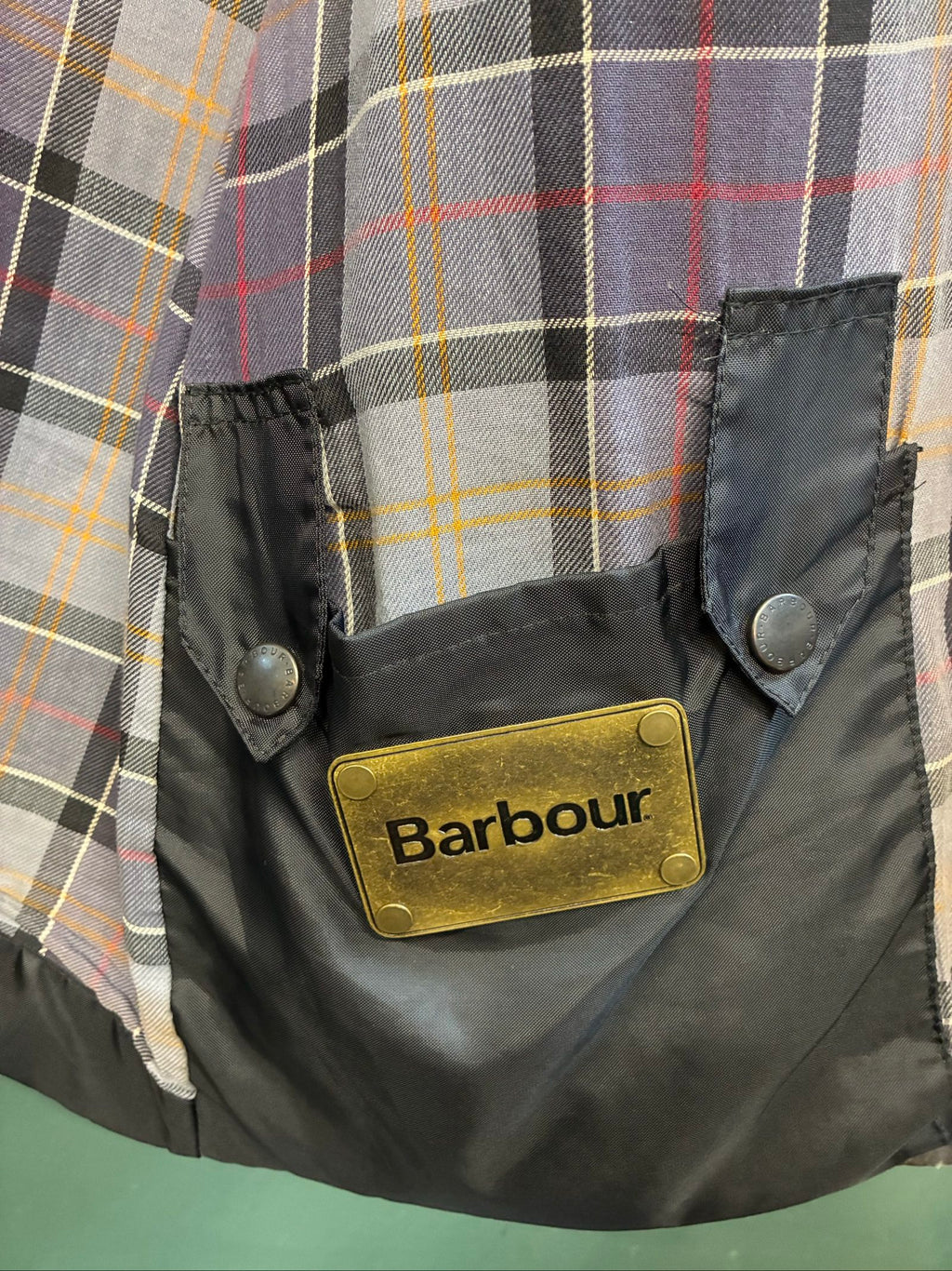 Barbour black and grey wax jacket with military utility design and made in England tag.
