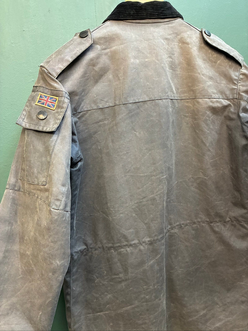 Barbour black and grey wax jacket with military utility design and made in England tag.