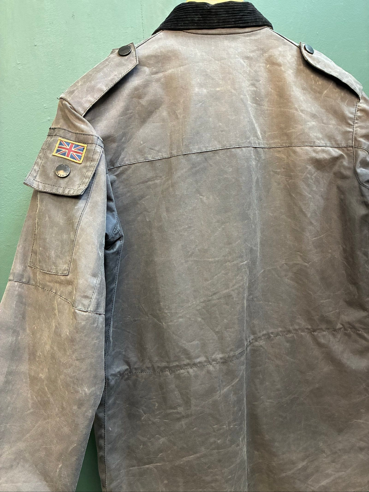 Barbour black and grey wax jacket with military utility design and made in England tag.