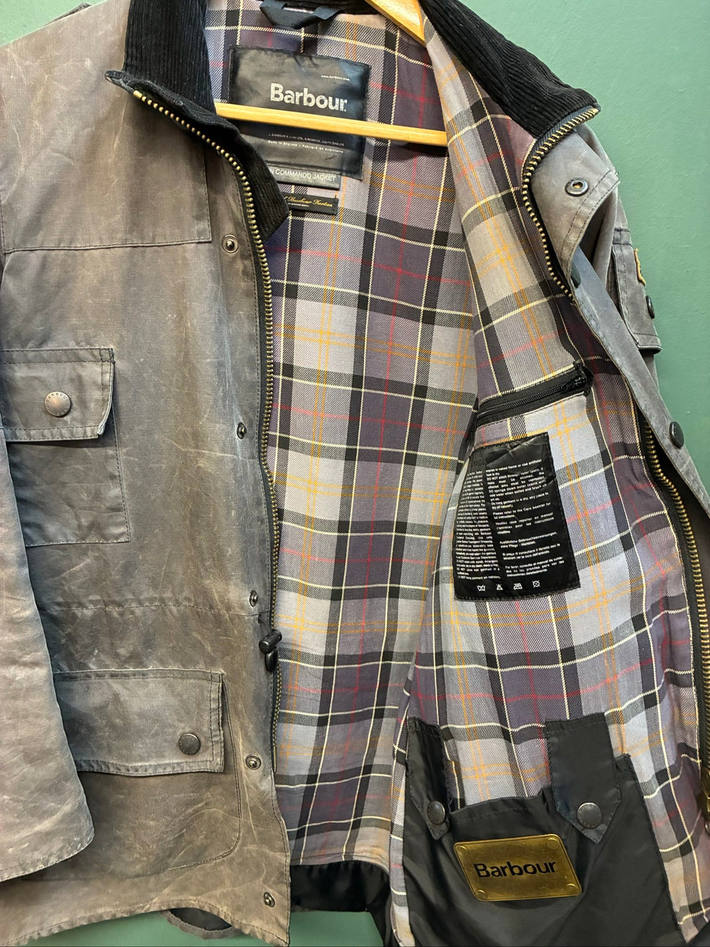 Barbour black and grey wax jacket with military utility design and made in England tag.